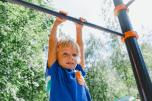 Hanging from the monkey bars is a fun outdoor sensory activity that build strength and coordination